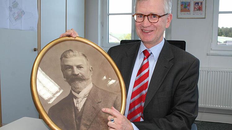 Er fühlt sich seinem Erbe verpflichtet und ist stolz auf 100 Jahre Rauschert Steinbach: Geschäftsführer Roland P. Rauschert mit dem Foto des Firmengründers Paul Rauschert. Foto: Veronika Schadeck