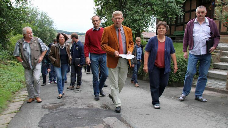 Ist die Straße "Am Greinberg" noch verkehrssicher oder muss sie dringend saniert werden? Diese Frage versuchten die Weitramsdorfer Gemeinderäte, angeführt von Bürgermeister Wolfgang Bauersachs (vorn), am Dienstagabend vor Ort zu klären. Eine knappe Mehrheit sah später bei der Abstimmung akuten Handlungsbedarf. Foto: Bettina Knauth