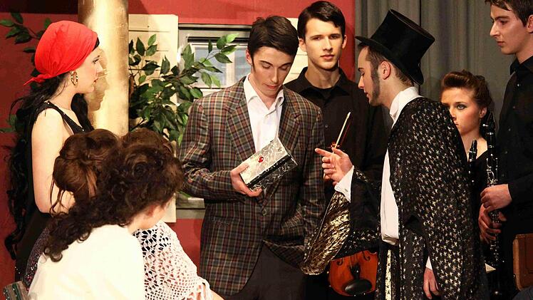 Der Zauberer Bastian Hunger überreicht dem Ehemann Simon Düsterdiek die Schatulle, Hotelmusiker, Gäste und Zauberergattin Lorena Helfrich schauen skeptisch zu. Foto: Thomas Dill