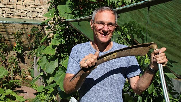 Manfred Nickel aus dem Hammelburger Stadtteil Obereschenbach mit einer Sense in seinem Privatgarten.
