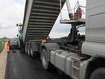 Straßensanierung bei Peesten (im Hintergrund): Ein Laster befüllt gerade den Asphaltfertiger mit neuem Material.  Fotos: Jürgen Gärtner