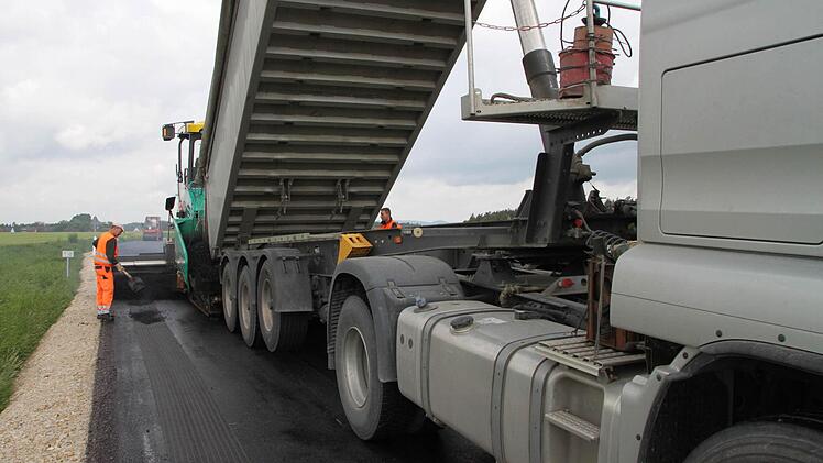 Straßensanierung bei Peesten (im Hintergrund): Ein Laster befüllt gerade den Asphaltfertiger mit neuem Material.  Fotos: Jürgen Gärtner