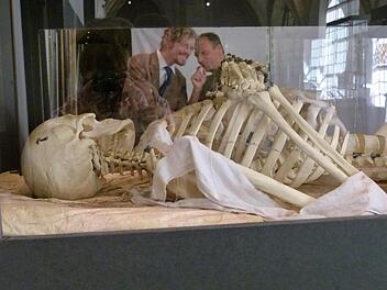 Museumschef Holger Kempkens (links) und Professor Ingolf Ericsson spiegeln sich in der Scheibe einer Vitrine, in der ein Skelett mit Rosenkranz zu sehen ist. Foto: Marion Krüger-Hundrup