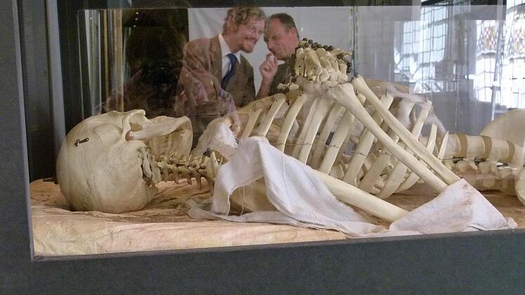Museumschef Holger Kempkens (links) und Professor Ingolf Ericsson spiegeln sich in der Scheibe einer Vitrine, in der ein Skelett mit Rosenkranz zu sehen ist. Foto: Marion Krüger-Hundrup