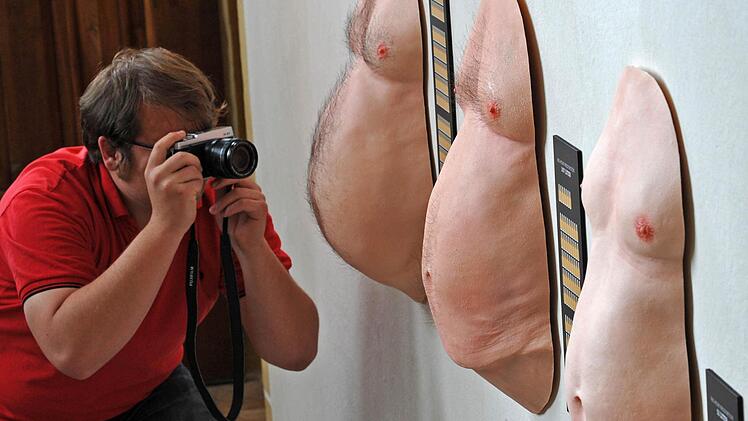 Ein Fotograf lichtet in einer Ausstellung in Meissen (Sachsen) die durchschnittlichen Bierbäuche des Sachsen (links), des Deutschen (Mitte) und des Hessen (rechts) ab.  Foto: Matthias Hiekel/dpa