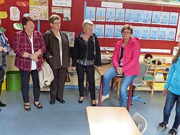 Die Schülerinnen Marie und Emilia sowie Schulleiterin Jasmin Müller-Alefeld (von rechts) zeigen den Besuchern, Schülern von damals, das Zimmer der jetzigen 1. Klasse. Foto: Bernd Brückner