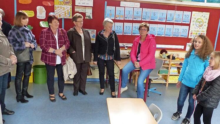 Die Schülerinnen Marie und Emilia sowie Schulleiterin Jasmin Müller-Alefeld (von rechts) zeigen den Besuchern, Schülern von damals, das Zimmer der jetzigen 1. Klasse. Foto: Bernd Brückner