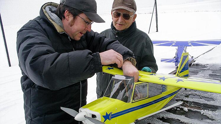 Auch im Winter sind die Kitzinger Modellbaufreunde aktiv. Eugen Hertel blickt Markus Forner über die Schulter, der seine Bellanca Citabria mit 1,8 Meter Spannweite vorbereitet. Um auf der verschneiten Piste starten zu können, wurde das Flugzeug auf Kufen umgebaut. Foto: Manfred Steinig