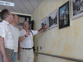 Edgar Buberl (links) und Wolfgang Kern (rechts) sind stolz auf ihre Ausstellung im Seniorendorf Kirschenallee. Einrichtungsleiter Matthias Hoderlein (Mitte) lässt sich genau erklären, was auf den Bildern zu sehen ist.