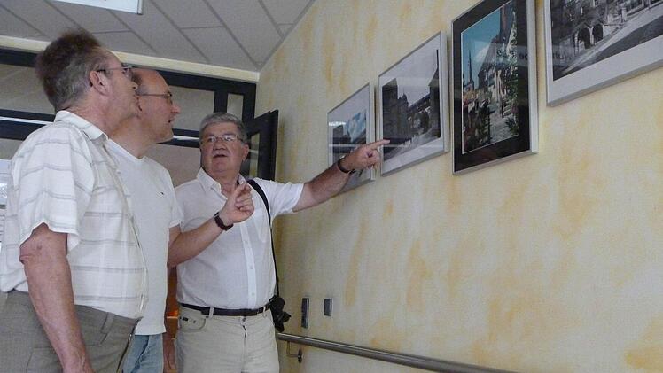 Edgar Buberl (links) und Wolfgang Kern (rechts) sind stolz auf ihre Ausstellung im Seniorendorf Kirschenallee. Einrichtungsleiter Matthias Hoderlein (Mitte) lässt sich genau erklären, was auf den Bildern zu sehen ist.