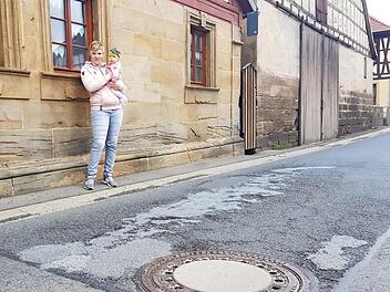 Sabrina Arnold mit Töchterchen Greta (ein halbes Jahr alt) an der ramponierten Straße vor ihrem Haus. Wenn Lkws durchfahren rumpelt's gewaltig. Foto: Eckehard Kiesewetter
