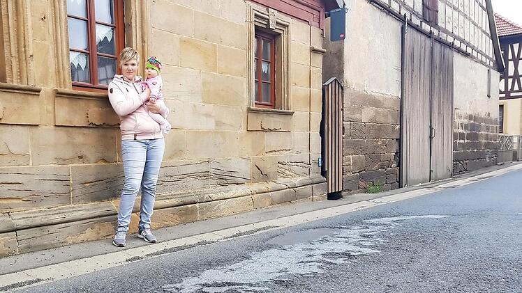 Sabrina Arnold mit Töchterchen Greta (ein halbes Jahr alt) an der ramponierten Straße vor ihrem Haus. Wenn Lkws durchfahren rumpelt's gewaltig. Foto: Eckehard Kiesewetter