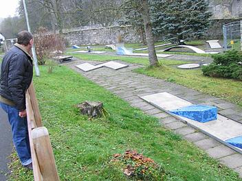 Ein Passant sieht sich die Minigolfanlage über den Zaun hinweg an. Foto: Walter Hanslok