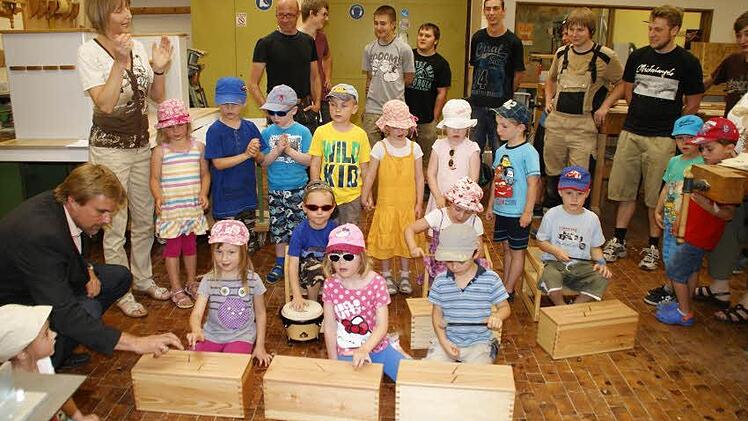 Außen Holz, innen Luft und Töne: mit Begeisterung testeten die Kinder die neuen Schlitztrommeln, die die Jungschreiner aus dem BGJ Holztechnik an der Berufsschule Haßfurt ihnen schenkten. Auch der stellvertretende Schulleiter Jochen Brüggemann (links) machte den Qualitätstest. Foto: sw