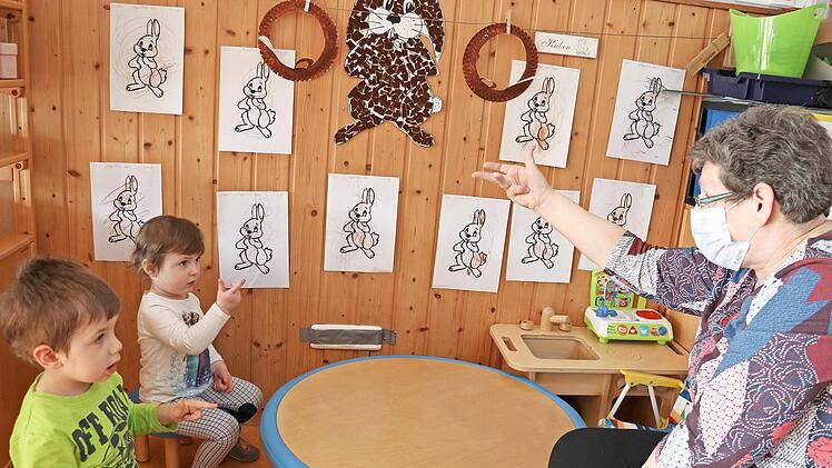 Mit Fingerspielen können die sprachlichen Fähigkeiten der Kinder gefördert werden, auch wenn Gruppenleiterin Sigrid Flurschütz eine Maske trägt. Deshalb schauen ihr Nico Geiger und Louise Albert ganz genau zu.