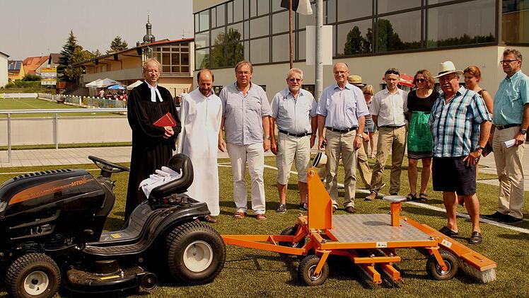 Das richtige "Werkzeug" hat man in Sand auch, um den Kunsrasenplatz angemessen pflegen zu können; unser Bild zeigt (von links): Pfarrer Hans-Christian Neiber, Pastoralreferent Rudi Reinhart, Bürgermeister Bernhard Ruß, Zweiten Bürgermeister Gerhard Zösch und Landrat Wilhelm Schneider bei der offiziellen Übergabe des neuen Platzes mit Platzwart Günther Flachsenberger ( Dritter von rechts) und dem neuen Pflegegerät. Foto: Günther Geiling