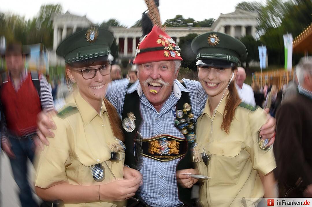 Der Münchner Vogelpfeiffer Horst Berger posiert mit den Wiesnpolizistinnen Anna und Lisa am 22.09.2015 in München (Bayern) auf dem Oktoberfest mit einer Vogelpfeife auf der Zunge. Die 182. Wiesn dauert bis zum 04.10.2015 und wird wieder rund sechs Millionen Besucher aus aller Welt anlocken. Foto: Felix Hörhager/dpa