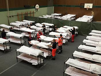 Betten beziehen im Akkord: In der Dreifachturnhalle stocken die BRK-Helfer am Sonntagnachmittag die Bettenkapazität auf, um vorübergehend 100 weitere Flüchtlinge unterbringen zu können. Foto: Maximilian Türk
