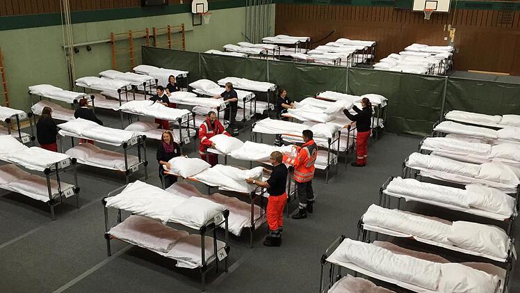Betten beziehen im Akkord: In der Dreifachturnhalle stocken die BRK-Helfer am Sonntagnachmittag die Bettenkapazität auf, um vorübergehend 100 weitere Flüchtlinge unterbringen zu können. Foto: Maximilian Türk