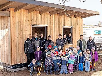 Das Bau-Team von Hanse Haus, Yanik Berberich (Leiter der KiTa St. Anna in Schondra) und die Kinderschar freuen sich &uuml;ber das neue Ger&auml;tehaus.