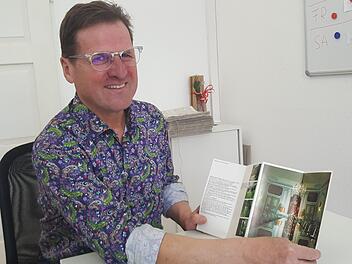 Alfons Hollet hatte zum Interview sogar ein Hemd angezogen, das an die 70er-Jahre erinnerte. Hier zeigt er einen Prospekt von Schloss Gymnich, seinem ersten Einsatzort als Personenschützer. Foto: Sabine Christofzik