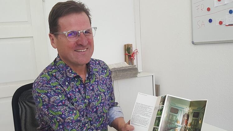 Alfons Hollet hatte zum Interview sogar ein Hemd angezogen, das an die 70er-Jahre erinnerte. Hier zeigt er einen Prospekt von Schloss Gymnich, seinem ersten Einsatzort als Personenschützer. Foto: Sabine Christofzik