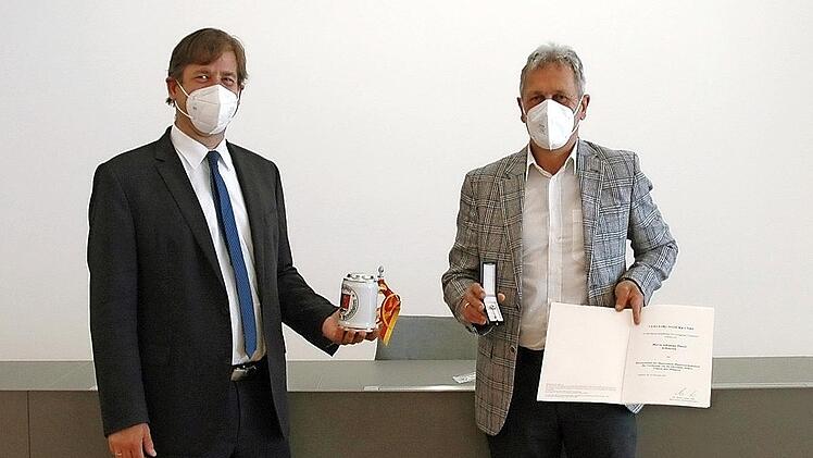 Landrat Hermann Ulm (l.) zeichnet Johannes Pinzel mit dem Ehrenzeichen des Ministerpräsidenten aus.