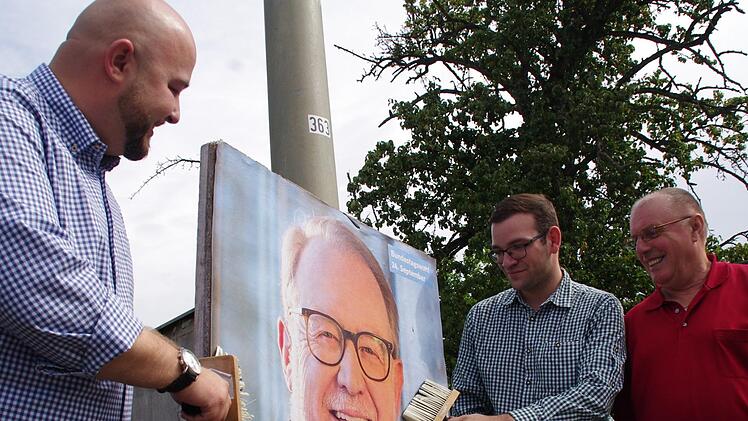 Nur noch wenige Plakate werden geklebt. Wenn, dann sind es meist die großformatigen, wie dieses von Hans Michelbach, das (v. l.) Jonas Geissler, Markus Oesterlein und Herbert Wachter in Kronach anbringen. Foto: Marco Meißner
