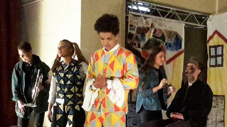 Die Harlekine stimmen das Publikum auf die Aufführung ein, während im Hintergrund noch improvisiert wird. Auch diese Szene gehört bewusst zur mehrschichtigen Handlung des brasilianischen Volksstückes. Foto: Rolf Pralle