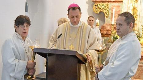 Weihbischof Herwig Gössl liest das Evangelium, an seiner Seite die Ministranten Regina und Michael.