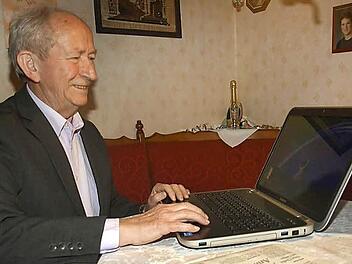 Siegfried Albert aus Ebenhausen mit Laptop und Saale-Zeitung: Der langjährige Kommunalpolitiker feiert am 12. Januar seinen 75. Geburtstag. Foto: Stefan Geiger