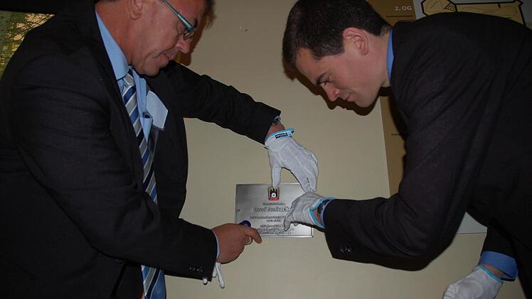 Stefan Grus (links) und Oliver Reidegeld installieren die Gedenkplakette für Josef Ambacher.