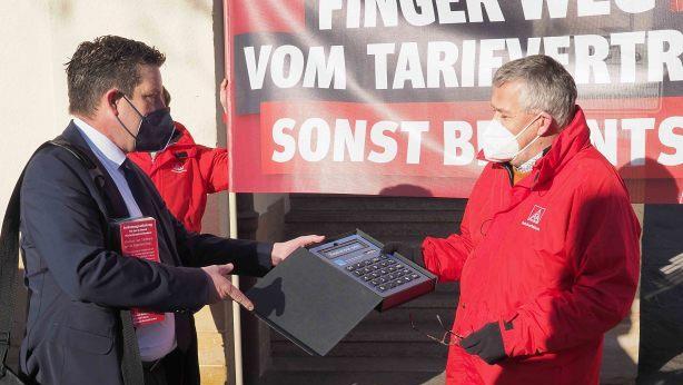 Symbolismus im Tarifkonflikt: Volker Seidel, 1. Bevollmächtigter der IG Metall Ostoberfranken (rechts), überreicht einen kleinen Feuerlöscher an David Püttner, Geschäftsführer des vbm Oberfranken. Der revanchiert sich mit einem umso größeren Taschenrechner, womit "Realismus" auszurechnen ist. Foto: Christoph Winter