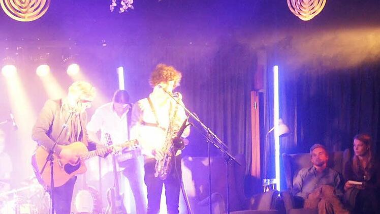 Samuel Harfst mit Band spielt auf der Bühne "Ein Privileg zu sein", während Samuel Koch (rechts) im Ohrensessel mitsingt.  Foto: Sarah Dann