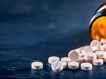 White medical pills or tablets with bottle on black background.