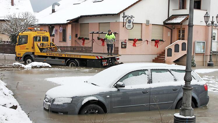 Georg Langosch (im Hintergrund) kam mit seinem Abschleppwagen nicht an den in den Fluten stehenden Audi heran. Die über die Ufer getretene Aisch hatte im Dezember 2010 das Sportgelände des ASV Höchstadt unter Wasser gesetzt.  Foto: Andreas Dorsch