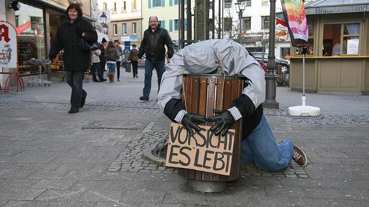 Den Kopf in der Mülltonne und ein Warnschild ,,Vorsicht: Es lebt!'' - das ist eines der neuen Kunstwerke, die die Schüler des Caspar-Vischer-Gymnasiums in der Innenstadt aufgestellt haben. Fotos: Sonja Adam