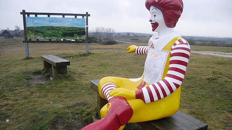 Ronald McDonald sitzt auf einer Bank neben der Panoramatafel am Görauer Anger und blickt ins Tal. Im Hintergrund ist der Kasendorfer Ortsteil Zultenberg zu sehen. Am Mittwoch endete der Ausflug von Ronald - McDonalds holte ihn zurück nach Kulmbach.Foto: Otto Arnold