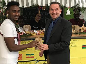 Alibona Abdulahi Mumed &uuml;berreicht Schulleiter Alexander Battistella eine Kostprobe der Geb&auml;ckspezialit&auml;ten aus aller Welt. Sonny Adam