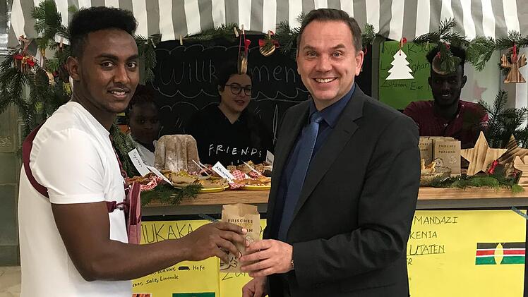 Alibona Abdulahi Mumed &uuml;berreicht Schulleiter Alexander Battistella eine Kostprobe der Geb&auml;ckspezialit&auml;ten aus aller Welt. Sonny Adam