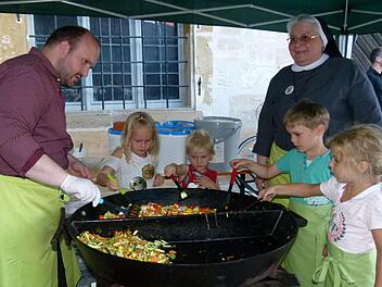 Die Kinder (v. l.) Antonia, Valentin, Felix und Noelani unterstützten Schwester Claudia Hink und Priesteramtskandidaten Sebastian Heim an der "Riesen-Veggi-Klosterküchenpfanne".  Fotos: Marion Krüger-Hundrup