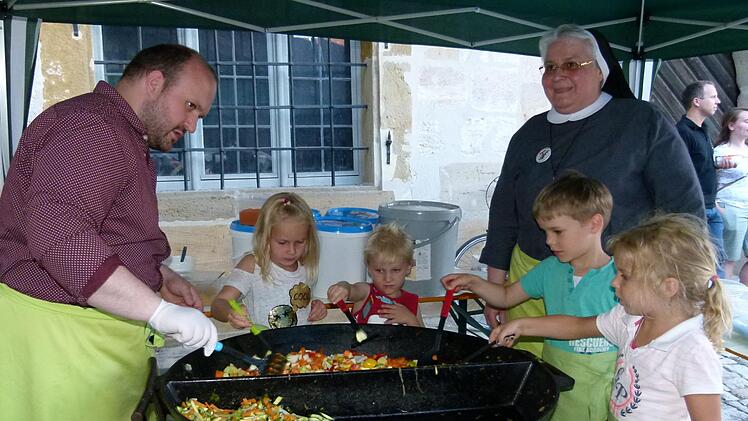 Die Kinder (v. l.) Antonia, Valentin, Felix und Noelani unterstützten Schwester Claudia Hink und Priesteramtskandidaten Sebastian Heim an der "Riesen-Veggi-Klosterküchenpfanne".  Fotos: Marion Krüger-Hundrup