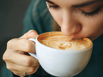 Kaffeeduft Kaffee Aroma Duft Morgen Cappuccino FlatWhite Milchschaum Crema Tasse Frau Genuss Hei&szlig;getr&auml;nk Dampf Nahaufnahme Ritual Fr&uuml;hst&uuml;ck Barista Bohnen R&ouml;stung Latte Art Espresso Alltag Hygge Zuhause W&auml;rme Entspannung Achtsamkeit Sinnesmoment Close up girl is drinking coffee. She enjoys her morning cappuccino or flat white.