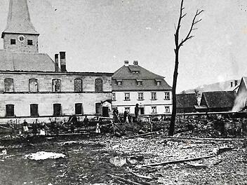 Die verheerende Feuersbrunst im Jahre 1906 hatte in Neukenroth ein Bild des Schreckens hinterlassen. Links zu erkennen sind Reste des abgebrannten Schulhauses, dahinter die örtliche Kirche St. Katharina sowie das Pfarrhaus. Rechts sind ein Teil der niedergebrannten Scheunen und Nebengebäude zu sehen.  Repro Gerd Fleischmann