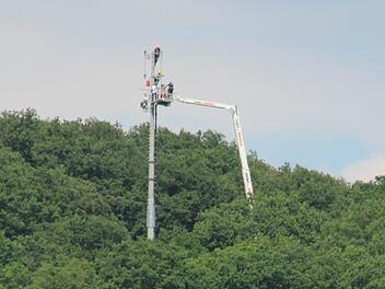 Arbeiten hoch über Ebern: Per Riesenkran lassen sich die Techniker zum Umsetzermast am Steinberg emporhieven, um den Netzausfall in den Griff zu bekommen. Foto: Eckehard Kiesewetter