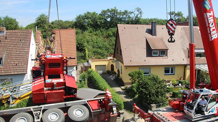 Der rote Autokran wollte den gelben, kleinen Kran im Vorarten absetzen, als er plötzlich in Schieflage geriet und umstürzte. Um ihm wieder auf die Reifen zu helfen, waren zwei weitere Autokräne gleichen Kalibers - ebenfalls 70-Tonner - nötig. Foto: Diana Fuchs