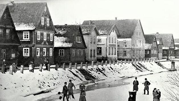 Auf dieser Aufnahme sind von links die Anwesen Fritz Hofmann, Georg Lieb, Johann Daum, Karl Heubach Karl M&uuml;ller, der Konsum und Therese Welscher (Romigkunzn) sichtbar. Vorne Dorfbewohner auf dem Eis des Ha&szlig;lachflusses.  Repro: Gerd Fleischmann