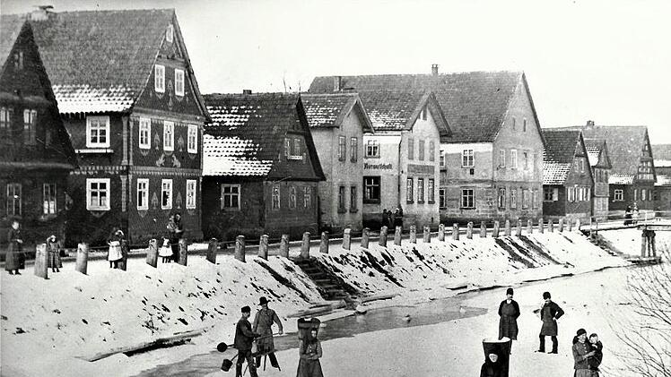 Auf dieser Aufnahme sind von links die Anwesen Fritz Hofmann, Georg Lieb, Johann Daum, Karl Heubach Karl Müller, der Konsum und Therese Welscher (Romigkunzn) sichtbar. Vorne Dorfbewohner auf dem Eis des Haßlachflusses.  Repro: Gerd Fleischmann
