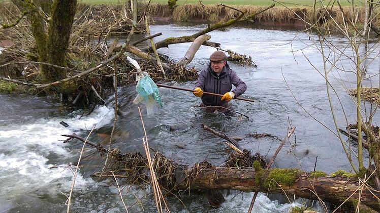 Nicht ungefährlich, was Wolfram Hoppe hier macht: Teils bis zur Brust im Wasser watend, holt er Plastikabfälle aus der Sinn. Foto: Karlheinz Franz
