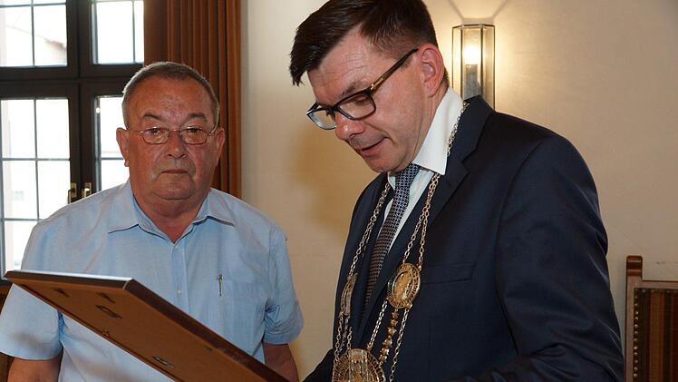 Bürgermeister Armin Warmuth (rechts) liest den Text der Dankurkunde für Hans-Dieter Scherpf vor. Foto: Arkadius Guzy